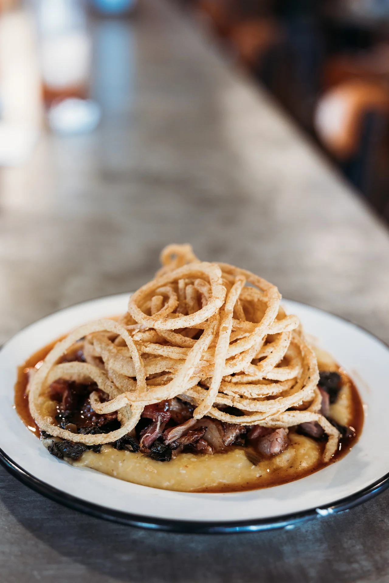 Pulled pork over creamy cheese grits with fried onion strings
